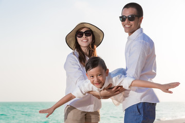 Asian family playing on the beach, Mother and father hold kid son on beautiful beach and sea