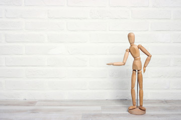 Wooden dummy in a proposing pose on the background of a white brick wall.