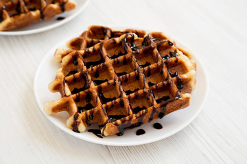 Yummy Homemade Belgian Sugar Waffles on a white plate on a white wooden background, low angle view.