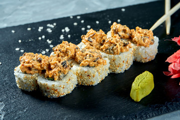 Appetizing Japanese sushi rolls - spicy with mussel on a black board on a gray background