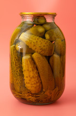 canned cucumbers in a jar on a pink background