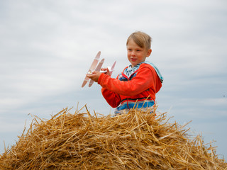 Naklejka na ściany i meble boy in the field playing with a toy airplane