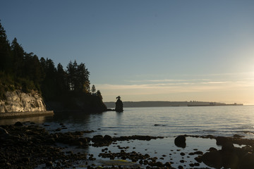 Siwash Rock and seawall at Stanley Park in Vancouver, Canada at Sunset. It is largest urban park with beaches, trails, scenic seawall. Top attraction for tourist in Vancouver, British Columbia