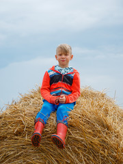 Naklejka na ściany i meble boy in the field playing on a stack of straw