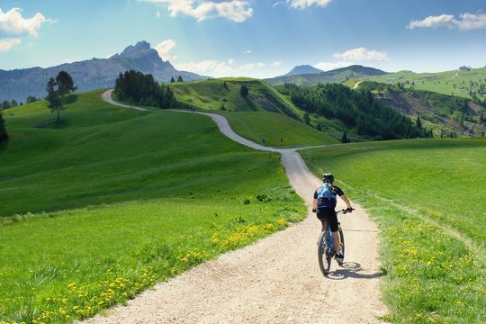 Biker riding scenic path in beautiful summer mountain scenery , Dolomites Italy, European Alps.