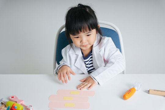 Asian Thai Kid Play Role As A Doctor Checking Medical Bandage Plaster.