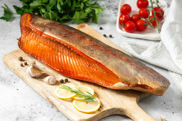 Smoked fish trout. Whole Smoked trout on the serving Board. Smoked trout lay on the light gray kitchen table. Smoked fish close-up	