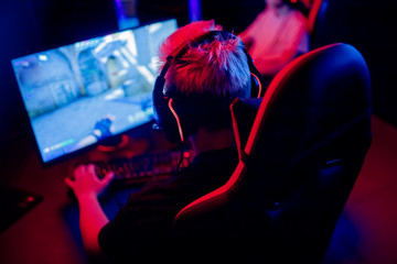 Professional gamer playing online games tournaments pc computer with headphones, Blurred red and blue background © Parilov