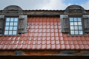 on the roof of the house covered with red tiles two Windows with shutters