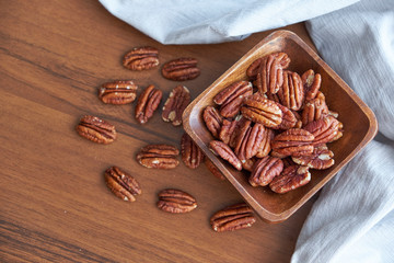pecan nuts in wood bowl on old brown table, selective focus. top view. Healthy food and snack.