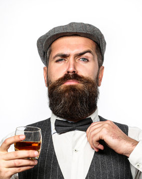 Macho drinking. Stylish rich man holding a glass of old whisky. Bearded gentleman drink cognac. Sipping finest whiskey. Portrait of man with thick beard