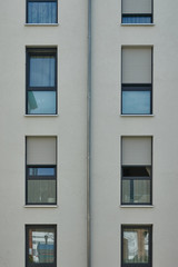 Strict looking perfectly rectangular facade of a residential building with windows and shutters, view from public ground