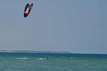 Brunette woman kitesurfing or kite boarding towards the camera on a sunny summer day in a front view to the camera