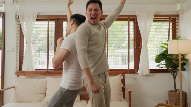 LGBT concept, Asian gay couple  just married homosexual couple  having fun sway dancing together in living room. Men raise hand and happy smile, enjoy music song at home. Happy gay couple portrait ind
