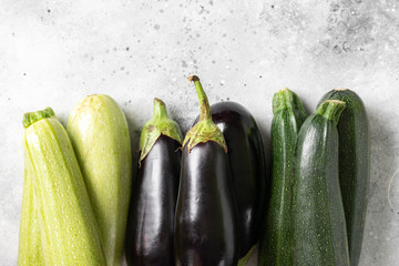 Raw zucchini and eggplant. Zucchini and eggplant on a light gray table. Top view with space for text. Harvest of zucchini and eggplant