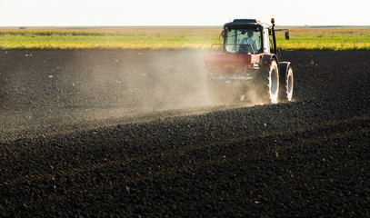Tractor spreading artificial fertilizers in field