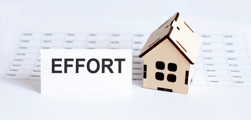 Closeup of house wooden model with blank for text EFFORT on the chart background.