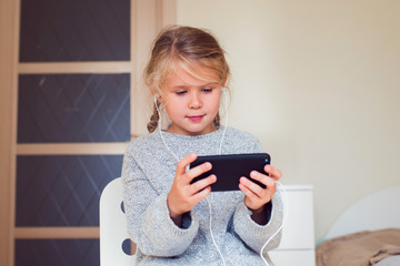 Kid using smartphone, girl in speakerphones playing or chating in social network, modern tecnology concept