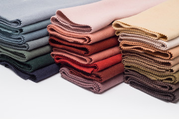 Polished woolen fabric, stacks on a white background close-up. Multi-colored textiles lie on a white background.