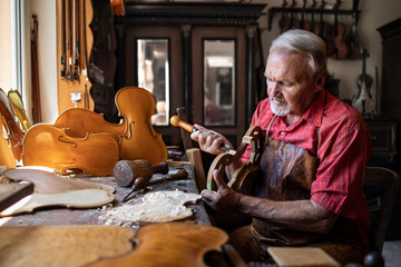 Arts and crafts. Senior carpenter craftsman carving wood in his old-fashion workshop. An experienced caucasian elderly man manually making masterpiece. Handcraft and creativity.
