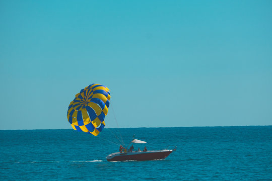 a boat with a parachute rides on the sea against the blue sky