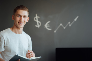 Smiling young man holding a folder with documents in his hands on the background of drawn business sketches