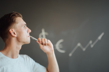 Fototapeta premium Smiling young man holding a folder with documents in his hands on the background of drawn business sketches