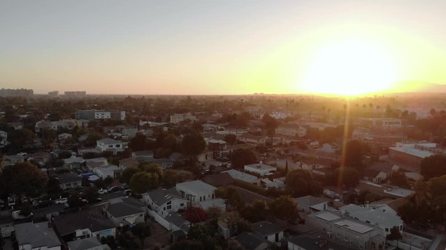 Aerial Rising over streets in Culver city neighborhood, during sunset, with mountains in background in Los Angeles, California, USA