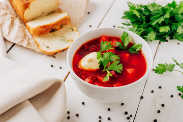 Borscht with fresh bread on a natural wooden background. Red beetroot soup with fresh bread