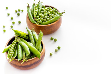 Set of green pea pods in wooden bowl on kitchen table desk