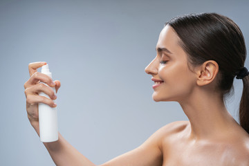 Woman spraying thermal water on her skin