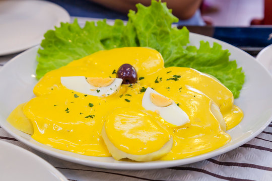 Papas a la Huancaína is a delicious Peruvian dish consists in sliced cooked potato with an aji and fresh cheese yellow sauce, boiled eggs and olives. Traditional Peruvian food concept.