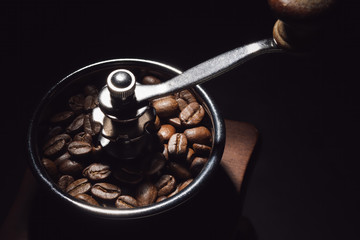 close-up photo of coffee beans in manual grinder machine in dark background