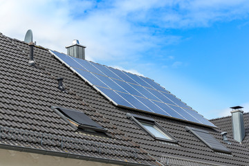 Hausdach mit Sonnenkollektor unterm blauen Wolken Himmel