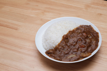 homemade Japanese curry rice with beef carrot beans and onion in white dish on wood table
