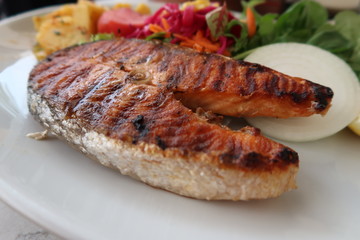 Salmon steak served with vegetables on the side.
