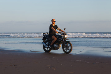 Fototapeta na wymiar Man on a motorcycle on the beach during sunset