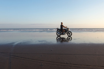 Man on a motorcycle on the beach during sunset