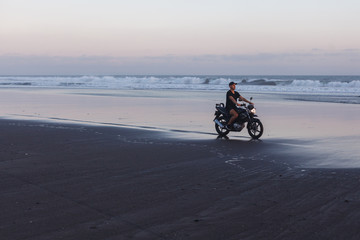 Man on a motorcycle on the beach during sunset