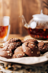 Teapot with black tea and homemade chocolate cookies on a brown natural wooden background
