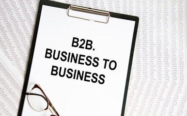 On the table are financial reports, a pen, a magnifying glass and a notebook with the inscription - B2B. Business to Business. Business and finance concept.
