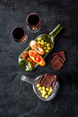 Toasts with prosciutto and tomatoes on glass bottle plate with red wine top view