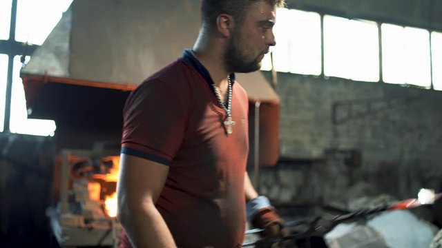 a blacksmith uses a hand hammer on an anvil to forge a red hot metal product