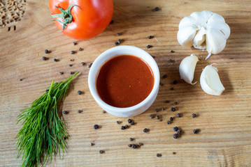 Obraz na płótnie Canvas ketchup in a bowl, fresh tomato, dill sprig and whole tomato close-up..