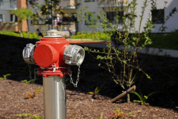 Painted steel hydrant stands on the lawn of a multistorey apartment. Fire hydrant at a public place. 