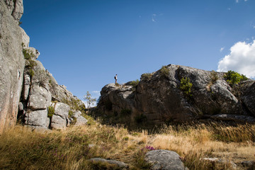 Hiker stands on top of a rock in the distance