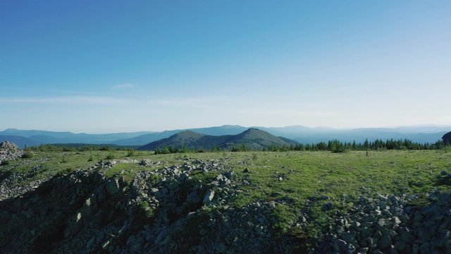Drone flies along the stone slopes of mount Bolshaya Suka in Ural. shadows of clouds on green mountain slopes