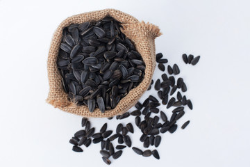 Burlap sack of sunflower seeds isolated on white background. Top view, closeup. Food, harvest,...