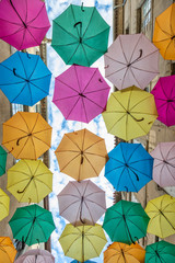 Fototapeta na wymiar Colorful umbrellas cover a shopping street in Carcassonne, Aude, Occitanie, France