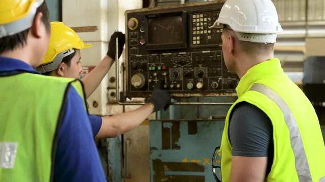 Three engineers discussed at a computer-based and tablet-based machine repair workshop explaining a work plan on how to perform the maintenance.